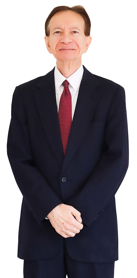 An adult man with hands crossed in front of him looks out at the camera. 