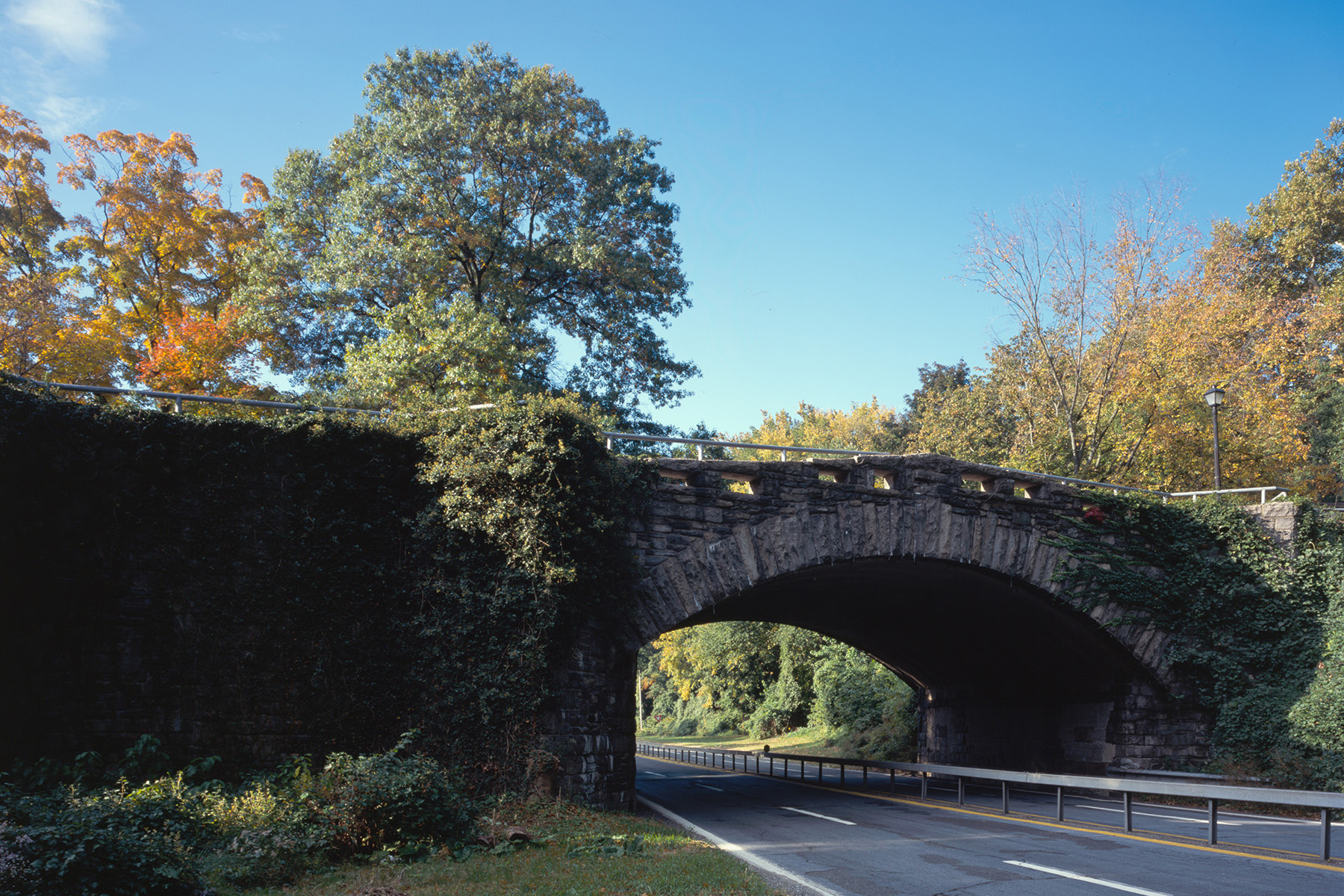 Image shows a four-lane parkway. Autumn-colored trees dot the landscape in the background.