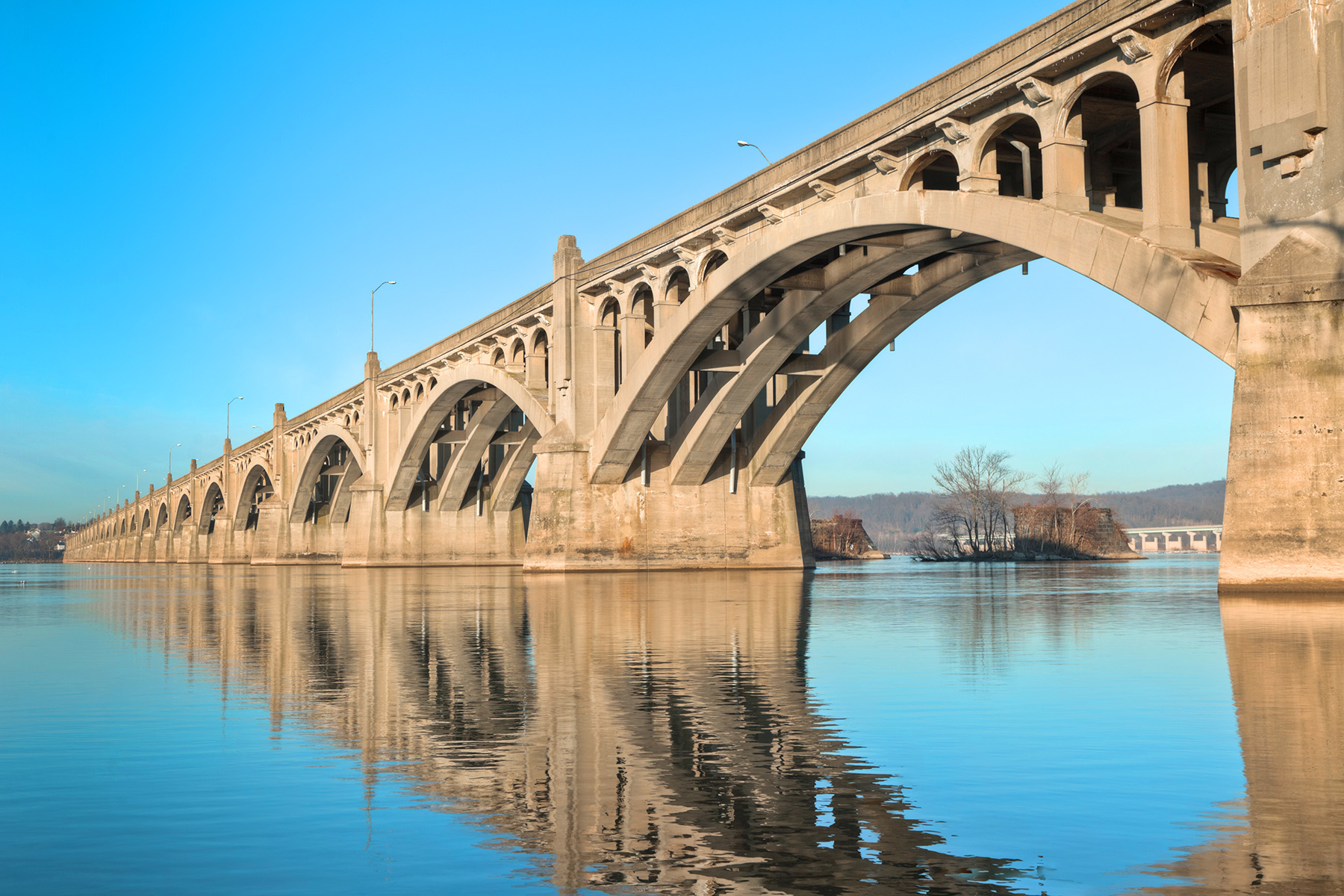 Photograph of a long concrete bridge over water that has many arches. 