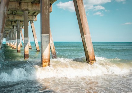 The ocean splashes around concrete piers.