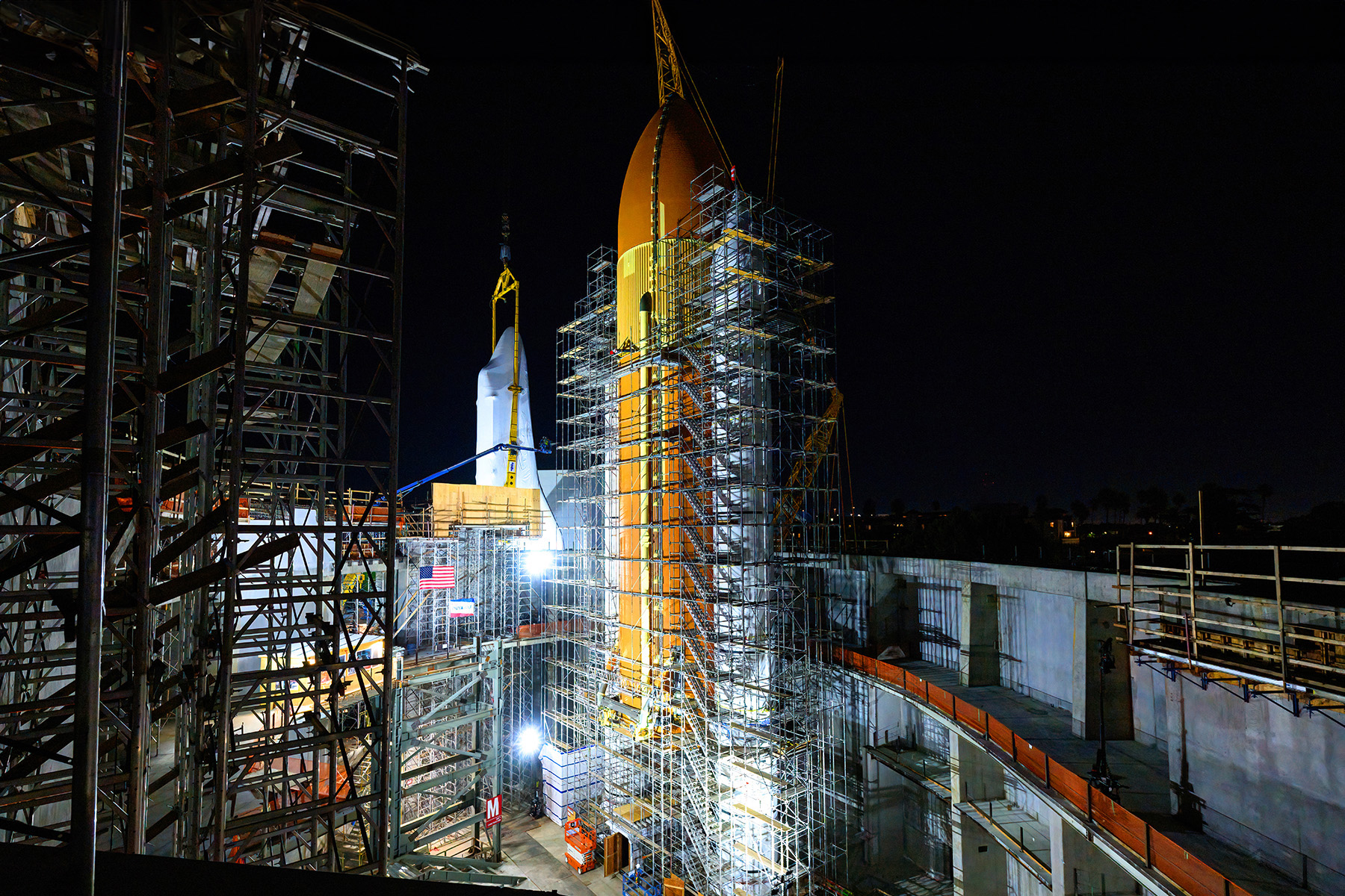 Surrounded by metal scaffolding, the shrouded shuttle is raised into position to attach to its external tank.