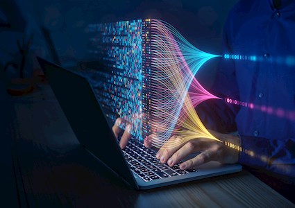 Hands type at a keyboard. In the foreground is an array of zeros and ones in various colors. 