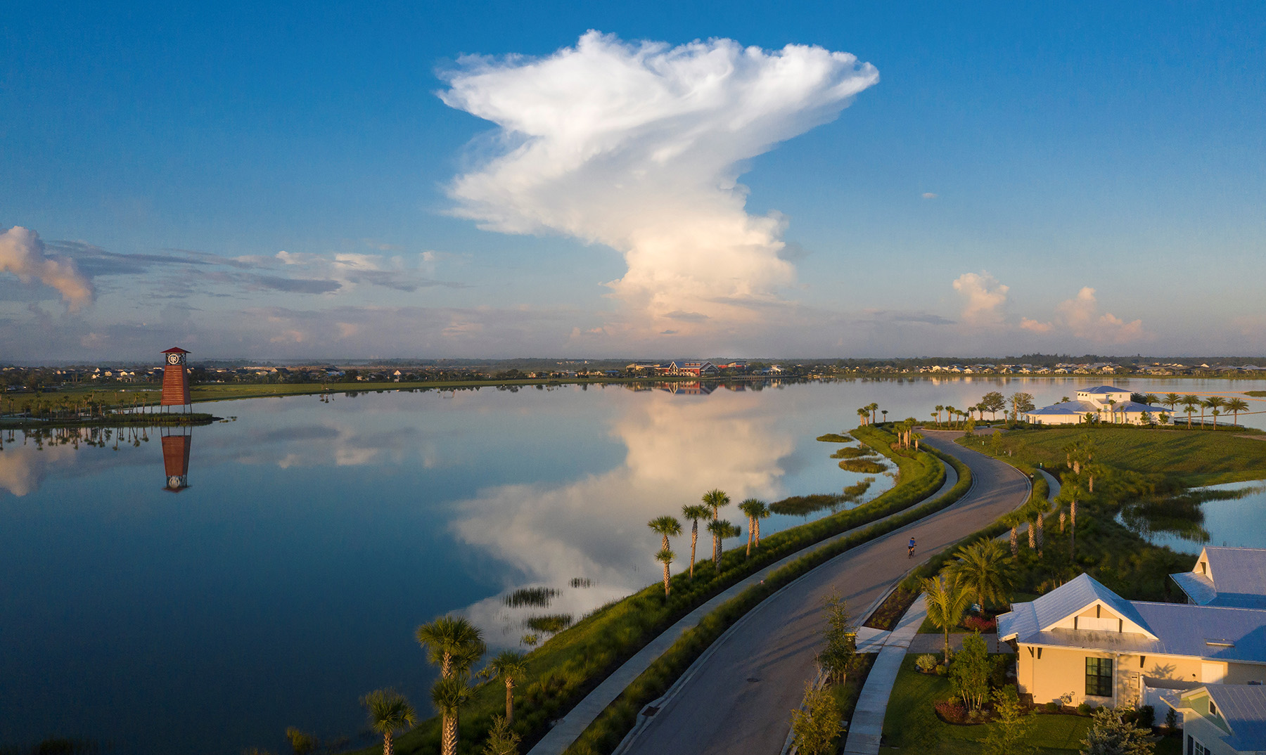 Trails and a lighthouse-like structure flank a large lake. 