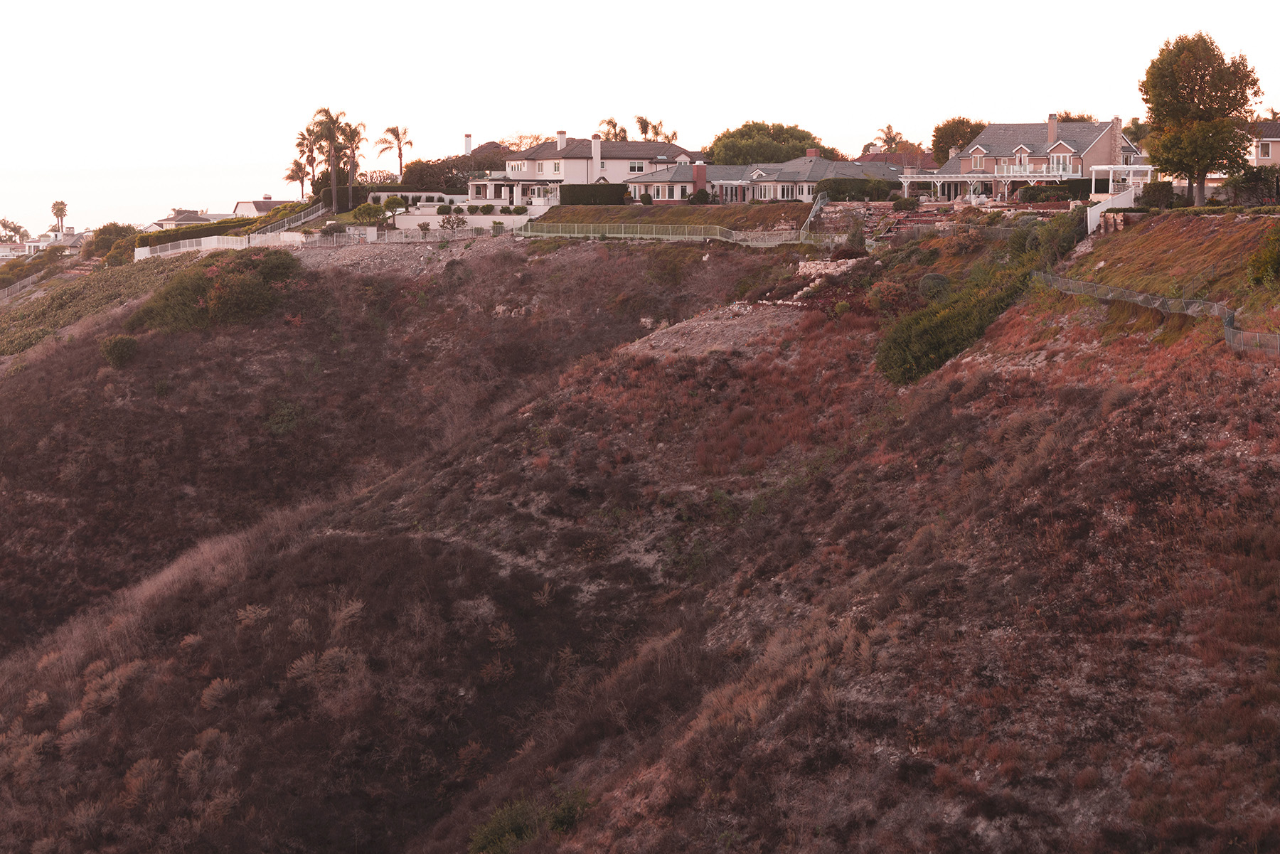 Houses sit precariously atop a hillside that has partially collapsed. Photograph
