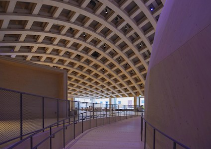 The interior of the Wisdome Stockholm depicts the crisscrossing roof beams and the edge of the domed arena. 