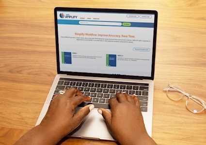 Hands typing on a laptop displaying the ASCE AMPLIFY online tool