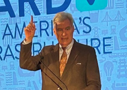 man in a suit points upward with his right hand