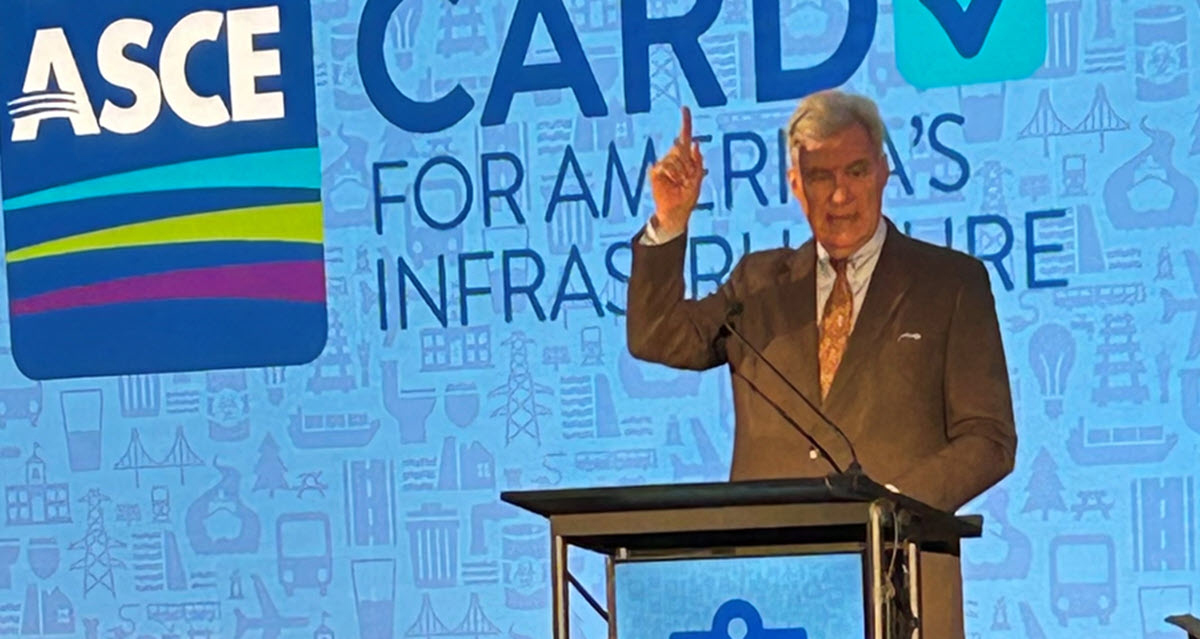 man in a suite points upward with his right hand