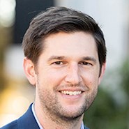 Man in jacket and shirt smiles at the camera.